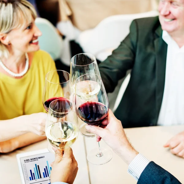 Trois personnes portent un toast avec des verres de vin lors d'une dégustation pour entreprises.