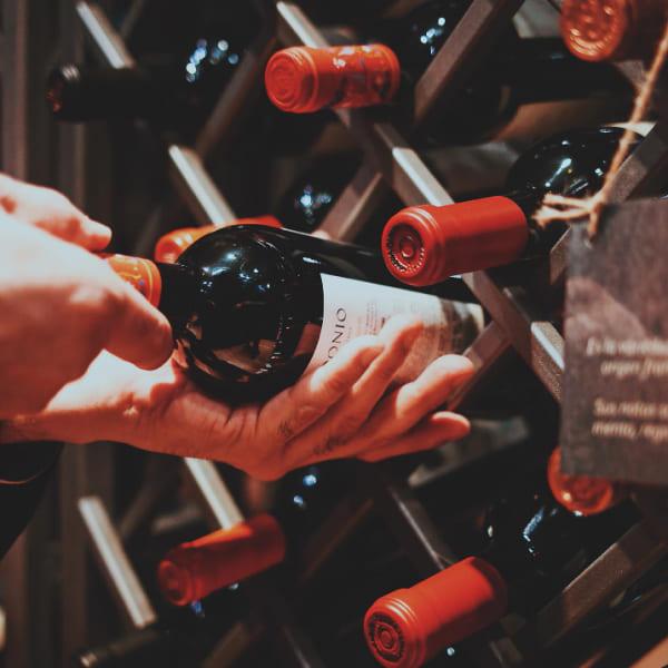 Une personne choisissant du vin dans un casier à bouteilles.
