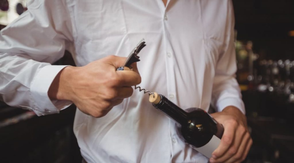 Une personne débouchant une bouteille de vin lors d'un événement